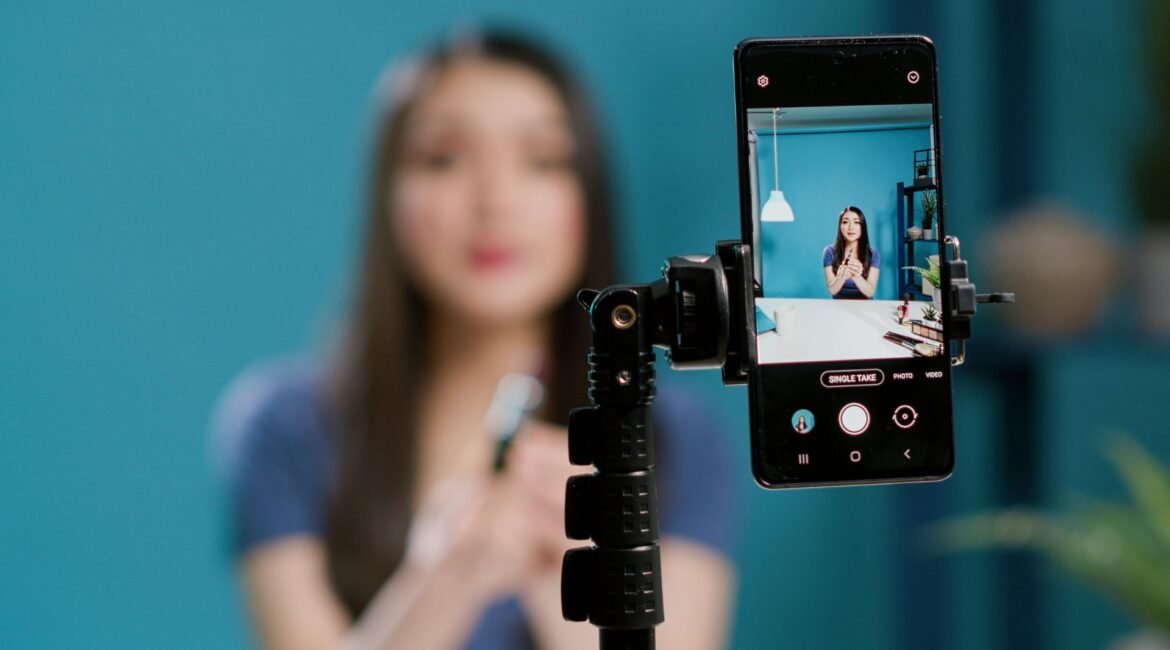 Microinfluencer grabando un video con su smartphone en un trípode; la pantalla del móvil enfoca a la creadora