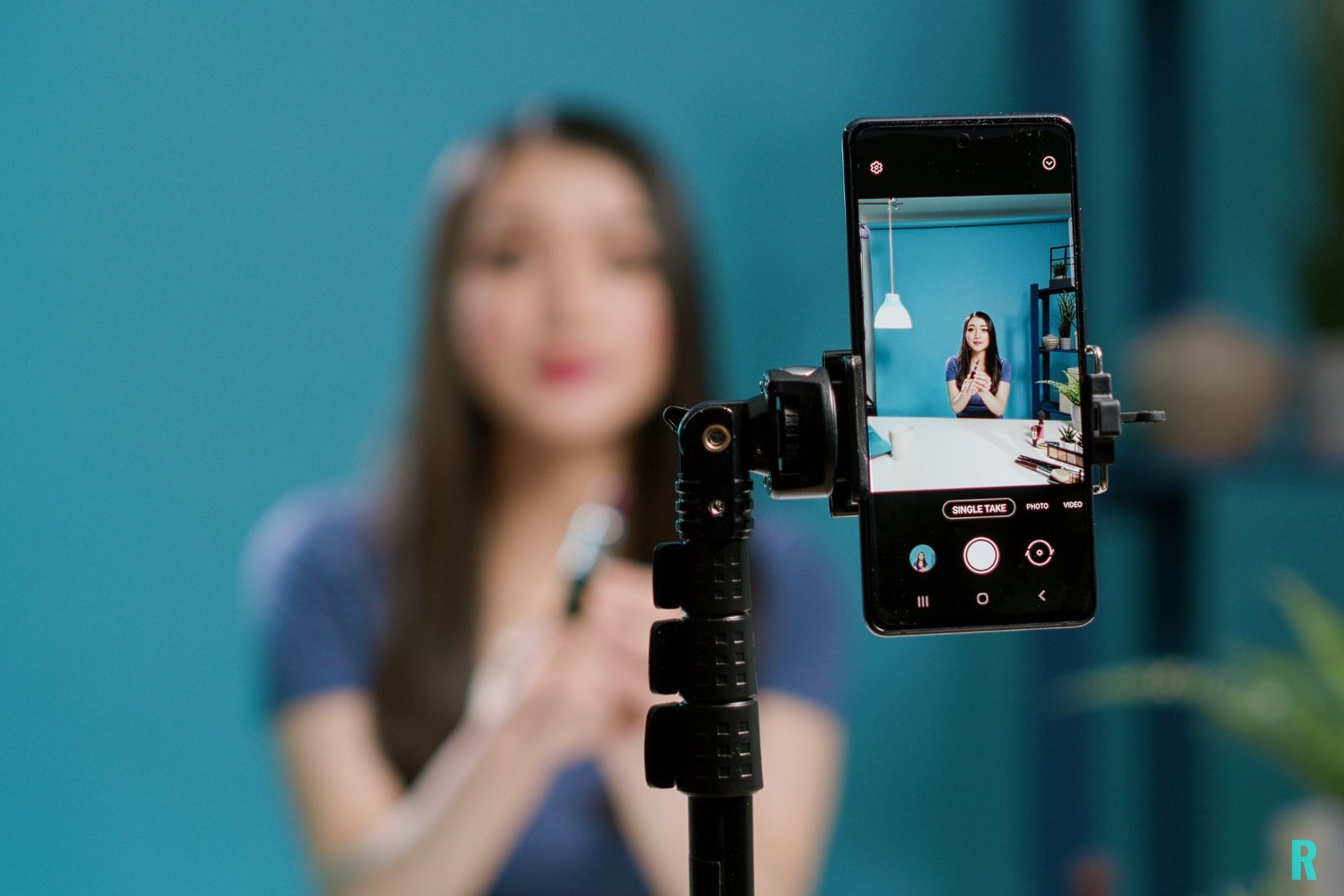 Microinfluencer grabando un video con su smartphone en un trípode; la pantalla del móvil enfoca a la creadora